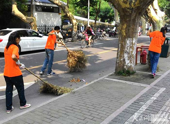 志愿者幫助環(huán)衛(wèi)工人清掃馬路。